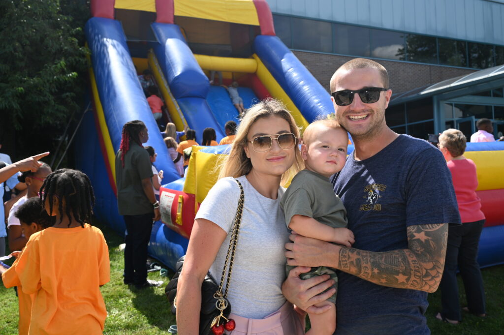 Family with a young child enjoying the Victory Church Tailgate near a colorful inflatable slide.