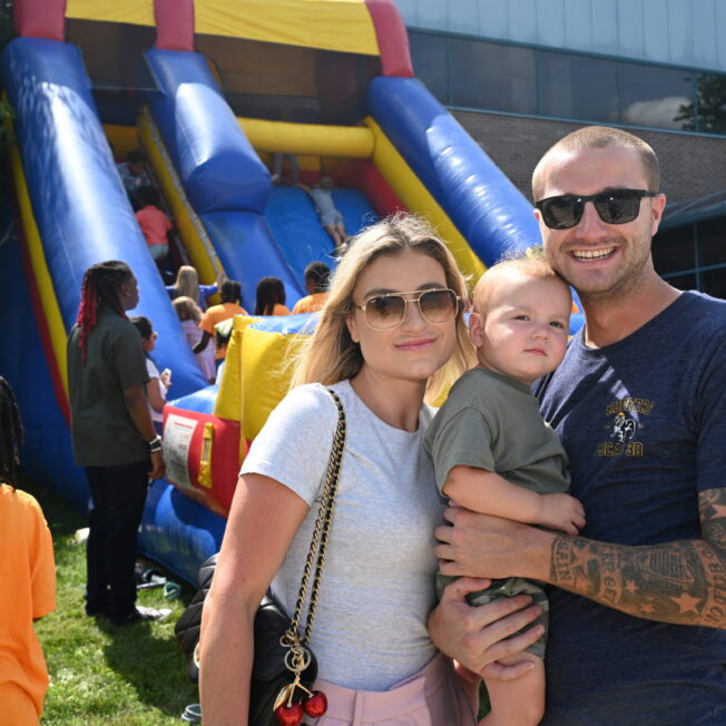 DSC_5155 — Family and children's activities Family with a young child enjoying the Victory Church Tailgate near a colorful inflatable slide.